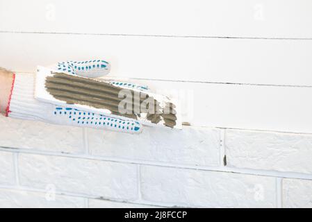 Professional Builder gluing decorative tile on wall. worker mounts decorative brick on wall. Stock Photo