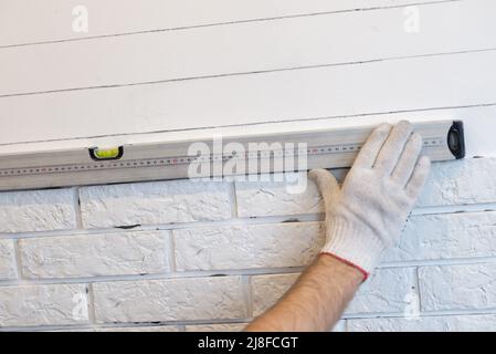 Professional Builder gluing decorative tile on wall. worker mounts decorative brick on wall. Stock Photo