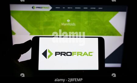 Person holding mobile phone with logo of American oil and gas company ProFrac Services on screen in front of web page. Focus on phone display. Stock Photo