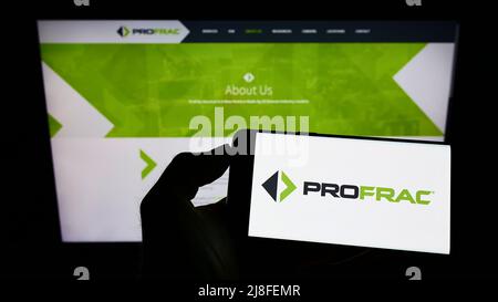 Person holding cellphone with logo of US oil and gas company ProFrac Services on screen in front of business webpage. Focus on phone display. Stock Photo