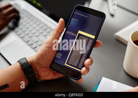 Close up of male IT developer holding smartphone with code on screen, copy space Stock Photo