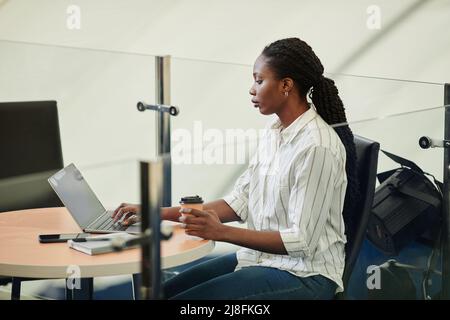 Side view portrait of young black woman using laptop in sports training center Stock Photo