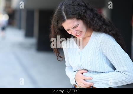 Stressed woman complaining in the street suffering belly ache Stock Photo