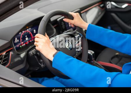 Side view of woman hands on the steering wheel driving a car, May 2022, Prague, Czech Republic Stock Photo