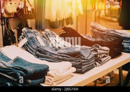 Stack Of Jeans On Shelves In Store Of Shopping Center. shelf display in shop mall store. Store Of Shopping Center. retail sale Stock Photo