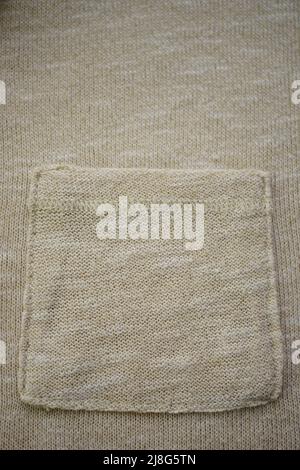 Beige sweater with pocket, knitted cream background Stock Photo
