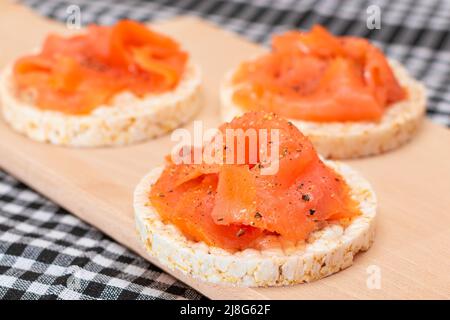 Tasty Rice Cake Sandwiches with Fresh Salmon Slices on Wooden Cutting Board. Easy Breakfast and Diet Food. Crispbread with Red Fish. Healthy Dietary Snack Stock Photo