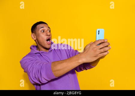 Portrait of attractive trendy amazed guy using gadget fast speed wow blog influencer isolated over bright yellow color background Stock Photo