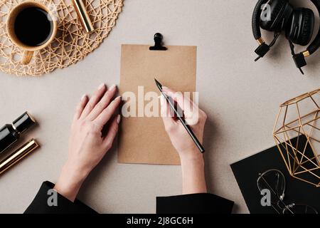 Hands of young creative female designer with pencil over blank paper drawing sketch for her new project while sitting by workplace Stock Photo