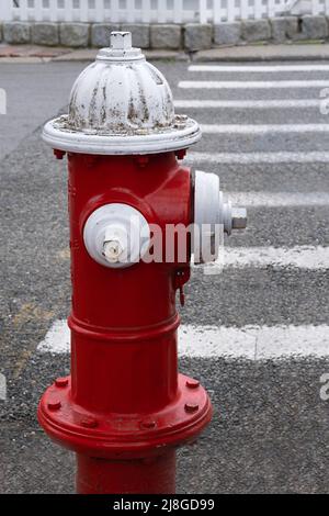 Red and white fire hydrant at end of street crossing white lines Stock Photo