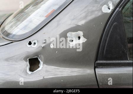 Close-up of the body of the shelled car. A sedan with through holes from shrapnel and bullets. The war in Ukraine 2022. Russian aggression. Shelling o Stock Photo