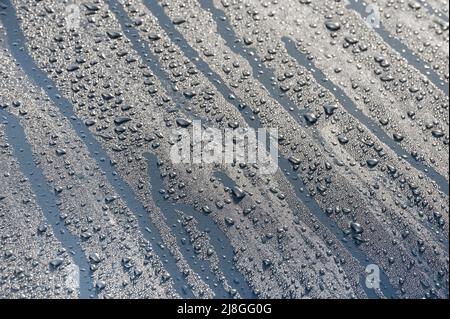 raindrops on a metallic vehicle hood under a blue sky Stock Photo