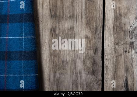 The blue checkered fabric lies against the wooden background. A towel or kitchen napkin on the rough boards or kitchen table. Stock Photo