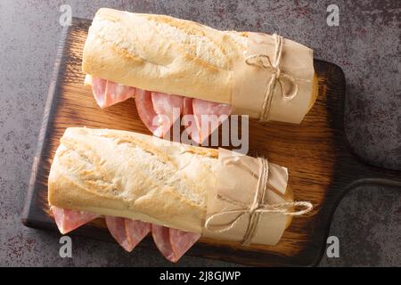 Jambon beurre is a simple and classic Parisian sandwich made with salted French butter and spiced ham closeup on the wooden board on the table. Horizo Stock Photo