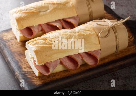 Jambon beurre is a simple and classic Parisian sandwich made with salted French butter and spiced ham closeup on the wooden board on the table. Horizo Stock Photo