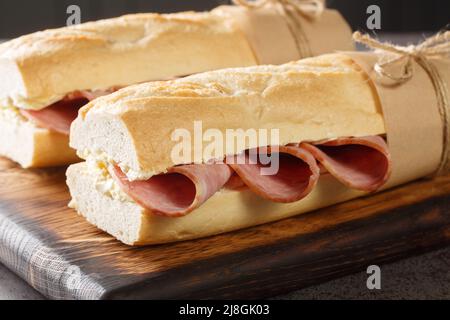 French Sandwich Jambon-Beurre made from a baguette with butter and ham closeup on the wooden board. Horizontal Stock Photo