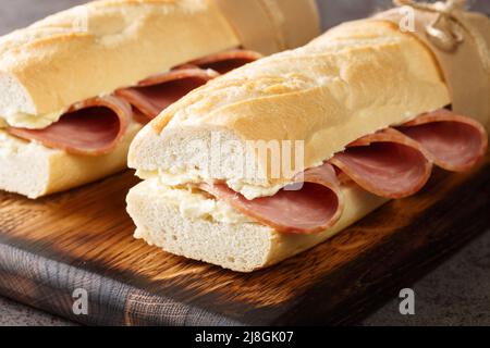 Classic Parisian Jambon-Beurre Sandwich closeup on the wooden board. Horizontal Stock Photo