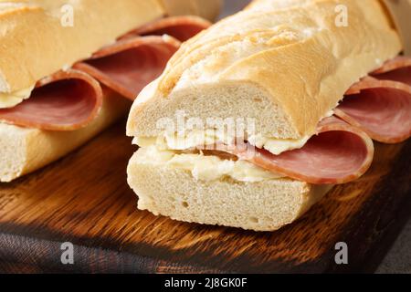 Tasty jambon-beurre is a French ham sandwich made of a fresh baguette sliced open, spread with salty butter, and filled with slices of ham Stock Photo