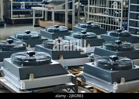 Group of new industrial machines parts prepared for assembly standing on crates in warehouse or workshop of modern factory Stock Photo