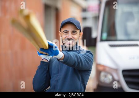 cheerful builder carries wood on his shoulder Stock Photo
