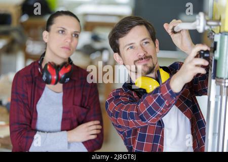 portrait of engineer and apprentice examining component in factory Stock Photo
