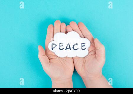 Holding a cloud with the word peace in the hands, stop war, support Ukraine, living peaceful together, color of ukrainian flag Stock Photo