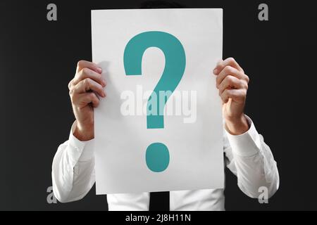 Perplexed businessman holding paper with question mark printed, selective focus Stock Photo
