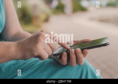 Woman using smartphone outdoors in the park, close up of female hands with mobile phone, selective focus Stock Photo