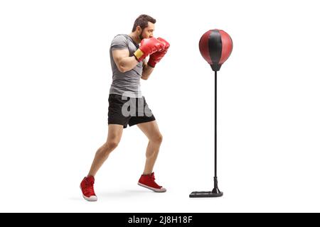 Full length profile shot of a boxer with red boxing gloves training with a free stand punch bag isolated on white background Stock Photo