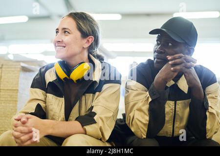 Two workers in uniform sitting and resting during break at warehouse Stock Photo