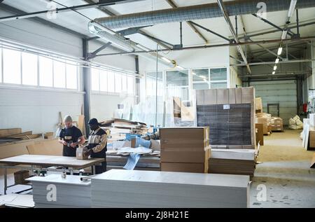 Image of big warehouse of furniture production with workers working in team Stock Photo