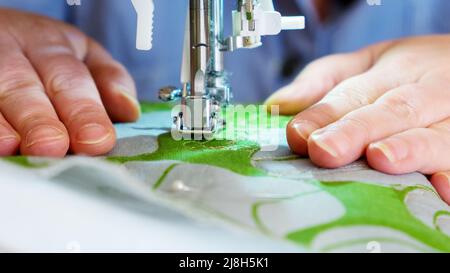Part of a sewing machine and a woman's hands close-up Stock Photo