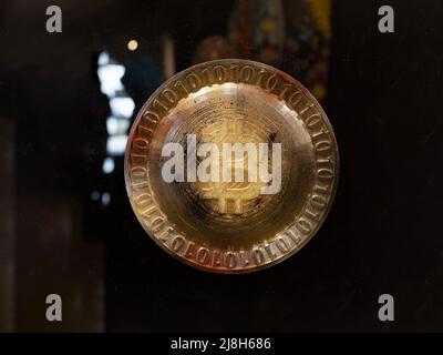 Bitcoin Symbol on a Round Golden Emblem Surrounded by Zeroes and Ones. Stock Photo