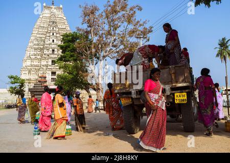 Hampi, Karnataka, India: A colourful group of women boards a lorry in front of the Sree Virupaksha Temple. Believed to be uninterruptedly functioning Stock Photo