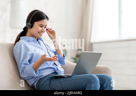 positive korean lady using headset and laptop at home Stock Photo