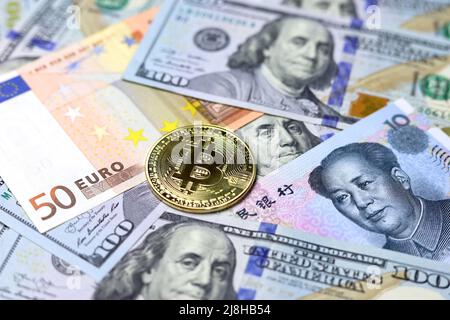 Bitcoin on US dollars, Chinese yuan and Euro banknotes. Concept of electronic decentralized money, crypto currency, global trade and economy Stock Photo