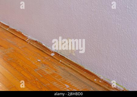 Old damaged concrete wall and parquet floor. Abandoned house with old weathered wall. Stock Photo