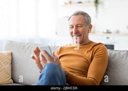 Happy mature man using cellphone wearing headphones Stock Photo
