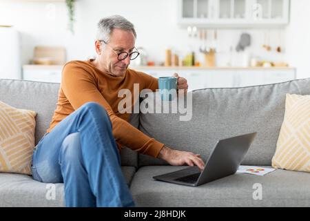 Mature man working on computer, drinking coffee Stock Photo