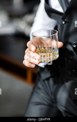 Groom in suit with whiskey glass at wedding. Stock Photo