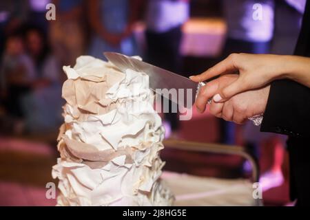Newlyweds cutting wedding cake in pastel colors. Stock Photo