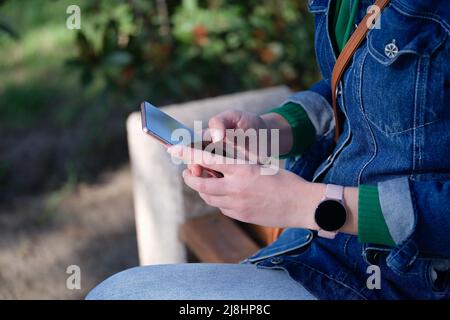 Woman relaxing in park and surfing internet on modern smartphone Stock Photo