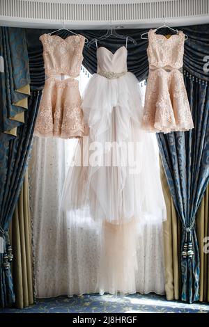 Wedding and bridesmaids dresses hanging by the window Stock Photo - Alamy