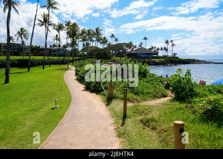 Walking path on the Kapalua Coastal Trail winding between luxury apartment buildings and the beach on Kapalua Bay in West Maui, Hawaii Stock Photo