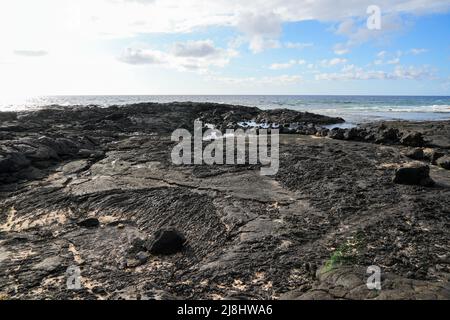 Solidified lava on the sandy O'oma Beach near Kailua-Kona in the west of Big Island in Hawaii, United States - Favorite getaway location among locals Stock Photo