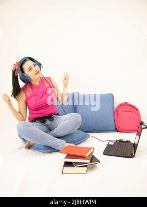 happy young student woman studying with headphones, books, web camera, computer and backpack Stock Photo