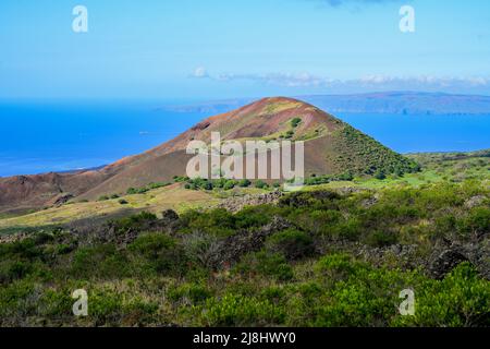 Volcanic crater on Piilani Highway in front of the Pacific Ocean with the West Maui Forest Reserve in the background Stock Photo