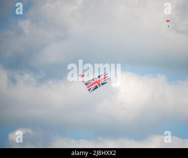 Parachute Regiment Freefall Team members of 'The Red Devils' practise over Netheravon Airfield, Large Union Flag in tow Stock Photo