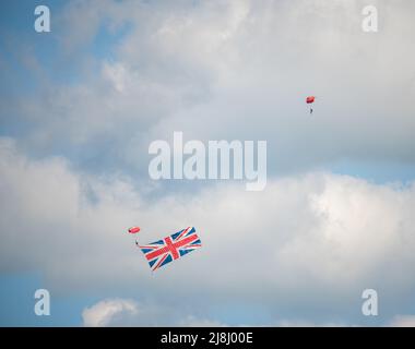 Parachute Regiment Freefall Team members of 'The Red Devils' practise over Netheravon Airfield, Large Union Flag in tow Stock Photo
