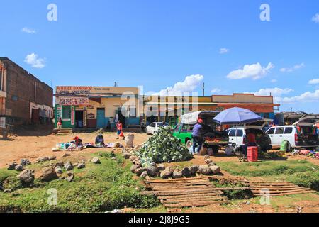 Market traders selling cabbage on dirt track of village street. Small shops including bookshop. Village in Kenya, Africa Stock Photo